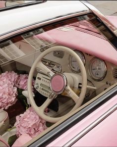 the interior of a pink car with flowers in the dash board and steering wheel on display