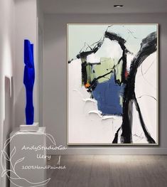 an abstract painting hangs on the wall next to a blue vase