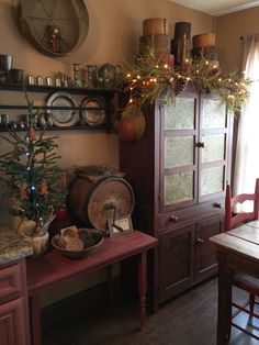 a christmas tree is on top of a hutch in the corner of a dining room