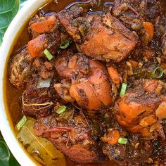 a bowl filled with meat and vegetables on top of a green leafy tablecloth