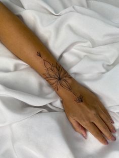 a woman's arm with a flower tattoo on the left side of her hand