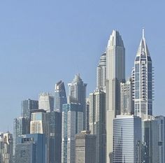 the city skyline is very tall and has many skyscrapers on each side, as well as boats in the water