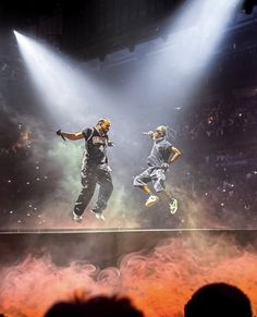 two people are performing on stage in front of an audience with their arms out and feet up