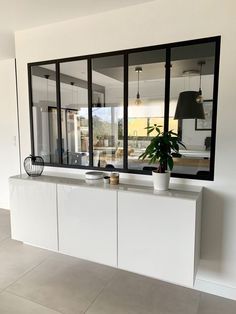 an empty room with large windows and a plant on the counter in front of it