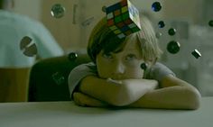 a young boy with a rubik cube hat on his head sitting at a table