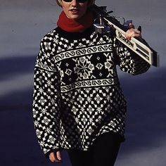 a woman walking down the street with a snowboard on her shoulder