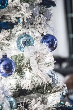 a white christmas tree decorated with blue and silver ornaments