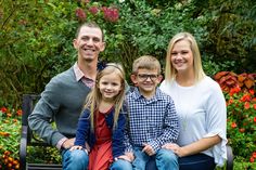 a family sitting on a bench in front of flowers