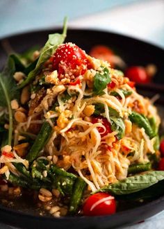 a black bowl filled with noodles and vegetables