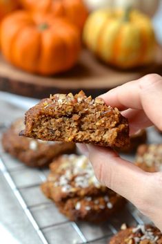 a person is holding up a cookie in front of some pumpkins and other food