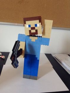 an image of a man made out of legos on a desk with other items