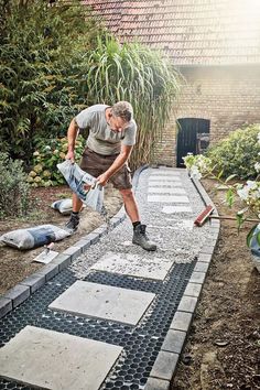 a man laying on the ground in front of a house with cement blocks and tools