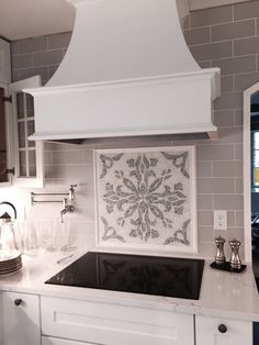 a kitchen with white cabinets and black counter tops, an oven hood over the stove