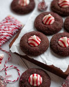 chocolate cookies with white and red candy canes on paper next to peppermint sticks