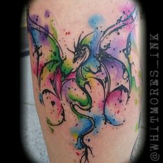 a colorful dragon tattoo on the leg with watercolor paint splatters all over it