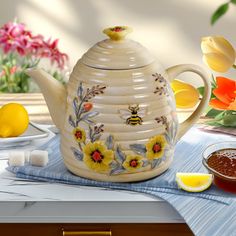 a tea pot with flowers painted on it next to some lemons and tulips