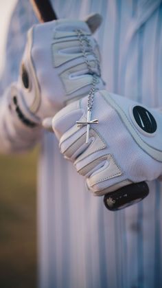 a close up of a person wearing white gloves and holding a baseball bat with a cross on it