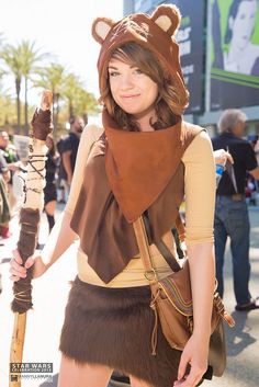 a woman dressed up as a bear holding a stick and wearing a scarf on top of her head