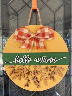 a wooden sign that says hello autumn hanging from a door hanger with a bow on it