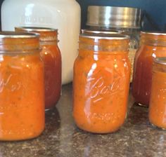 four jars filled with different kinds of sauce