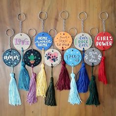 a bunch of key chains that have different designs and words on them with tassels