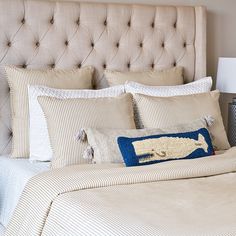 a bed with blue and white striped sheets, pillows and lamps on the headboard