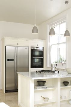 a kitchen with an oven, refrigerator and sink in it's center island next to a window