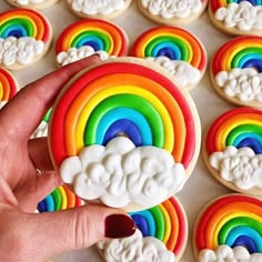 a rainbow cookie being held up by someone's hand with cookies in the background