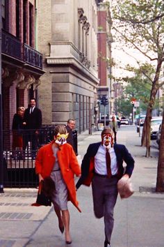 two people walking down the street with clown faces on their face and one person wearing a mask