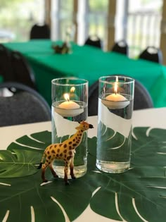 two giraffe figurines sitting on top of a table next to candles