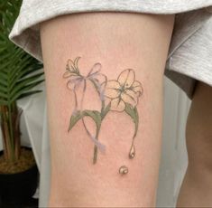 a woman's leg with a flower and water drop tattoo on her left thigh