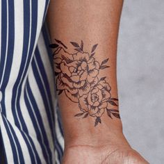 a woman's arm with a flower tattoo on her left wrist and right hand