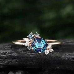 an engagement ring with blue and white stones on it, sitting on a piece of wood