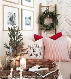 a basket filled with christmas decorations on top of a couch next to a pillow and candles