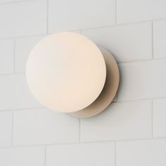 a white wall light mounted on the side of a brick wall with two circular lights