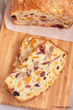 a loaf of fruit bread sitting on top of a wooden cutting board