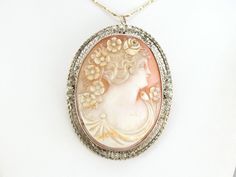 "Simply stunning, this lady is absolutely gorgeous! This vintage cameo pendant is immaculate, crafted of white gold with lovely scrolling filigree with floral details! Not only is the frame outstanding, but the level of detail and exquisite composition of the carved shell cameo are among the finest we've seen. Particularly lovely is the three-dimensional flowers that are carefully placed in the women's hair! This pendant does not come with the chain shown. Please feel free to contact us, we will Market Square, Cameo Ring, Vintage Cameo, Carved Shell, Cameo Brooch, Cameo Pendant, Hand Engraving, Vintage Brooches, Estate Jewelry