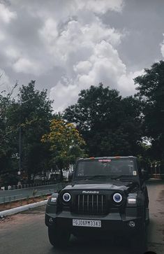 a black jeep driving down a street next to trees