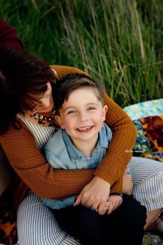 a woman hugging a young boy on the ground