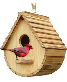 a red bird sitting on top of a wooden birdhouse