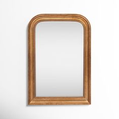 a large mirror hanging on the wall in front of a white wall with a wooden frame