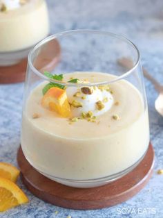 two desserts with orange slices and whipped cream in small glass dishes on a blue tablecloth