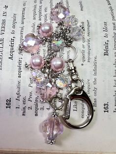 a book with a keychain and some beads on it's side, sitting on top of an open book