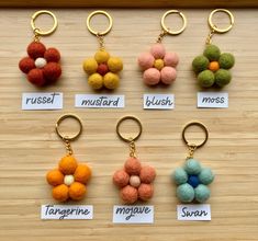 six key chains with different colored pom poms on them