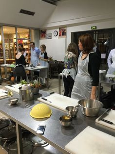 a group of people in a kitchen preparing food on top of a metal workbench