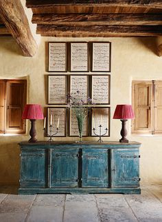 a blue cabinet with two lamps and pictures on the wall