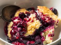 a close up of a bowl of food with blueberries and crumbs on it