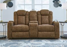 the reclining loveseat is in front of a window with two lamps on it