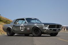 an old muscle car driving down the road with numbers painted on it's side