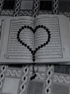 an open book with a rosary in the shape of a heart